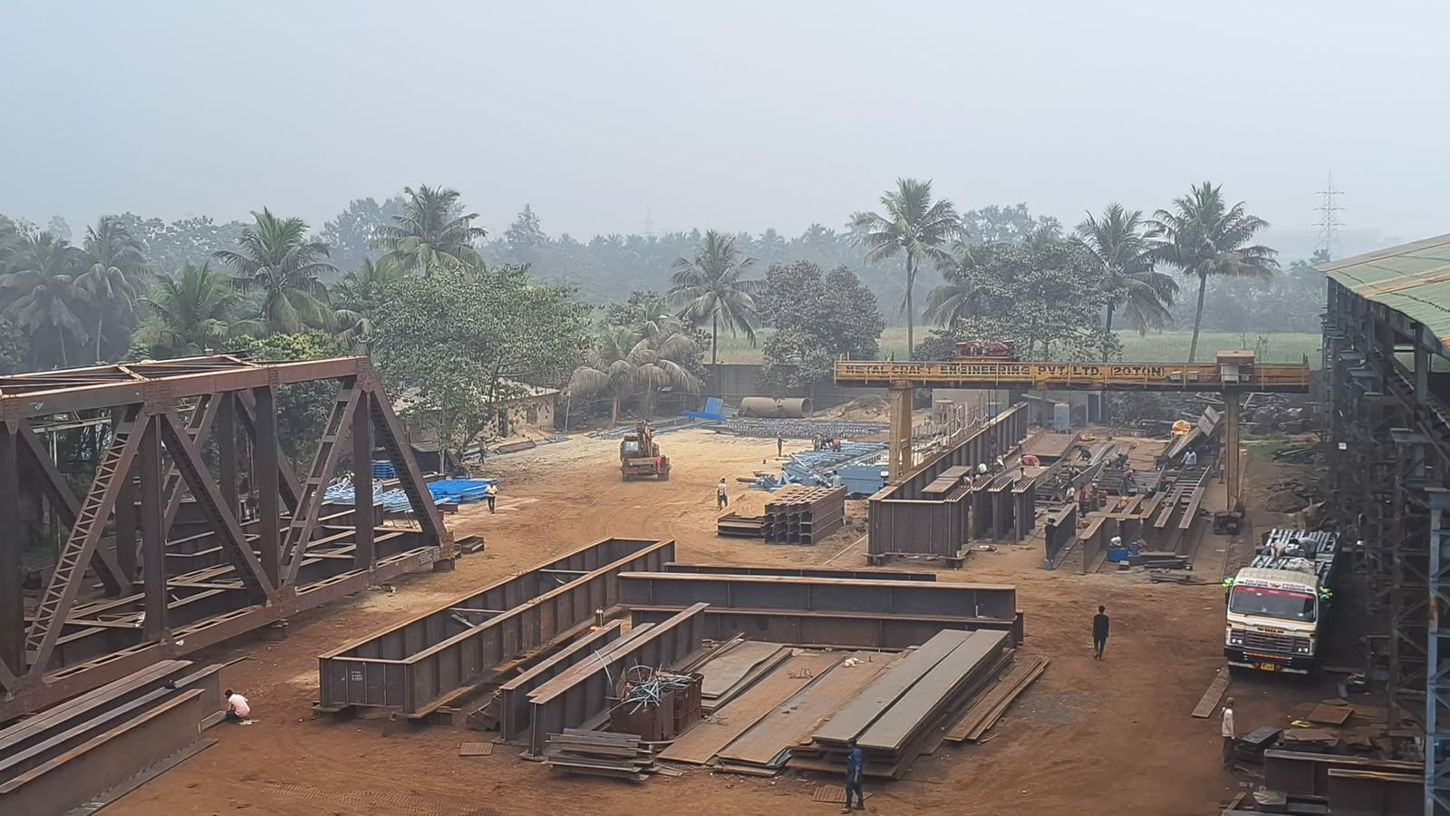 Steel truss girders, fabricated sections and plate laid out across the Metal Craft fabrication yard, Kolkata