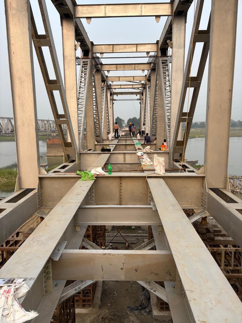 View along the deck of a painted steel truss span under construction, with its cross girders in place