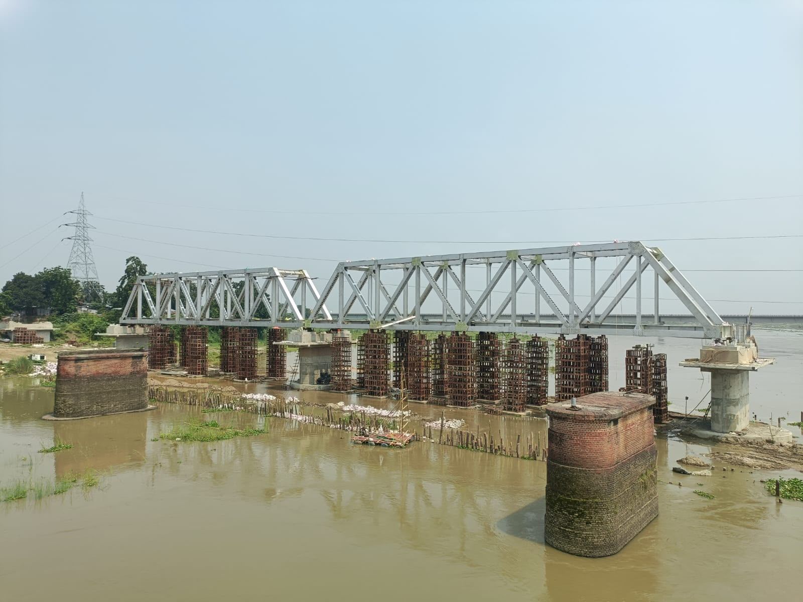 Grey-painted steel truss bridge span on piers across a river