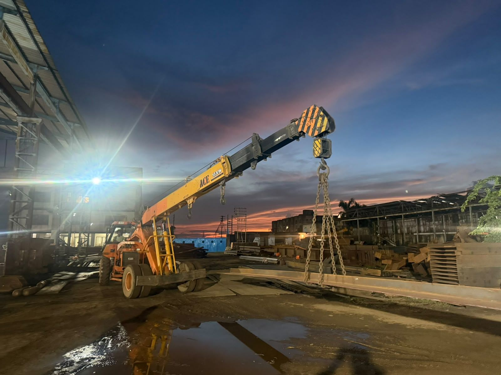 Mobile crane lifting steel plate in the Metal Craft fabrication yard, Kolkata, at dusk