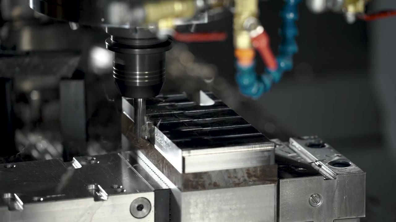 Illustrative photo: a CNC milling cutter machining a steel block under coolant lines