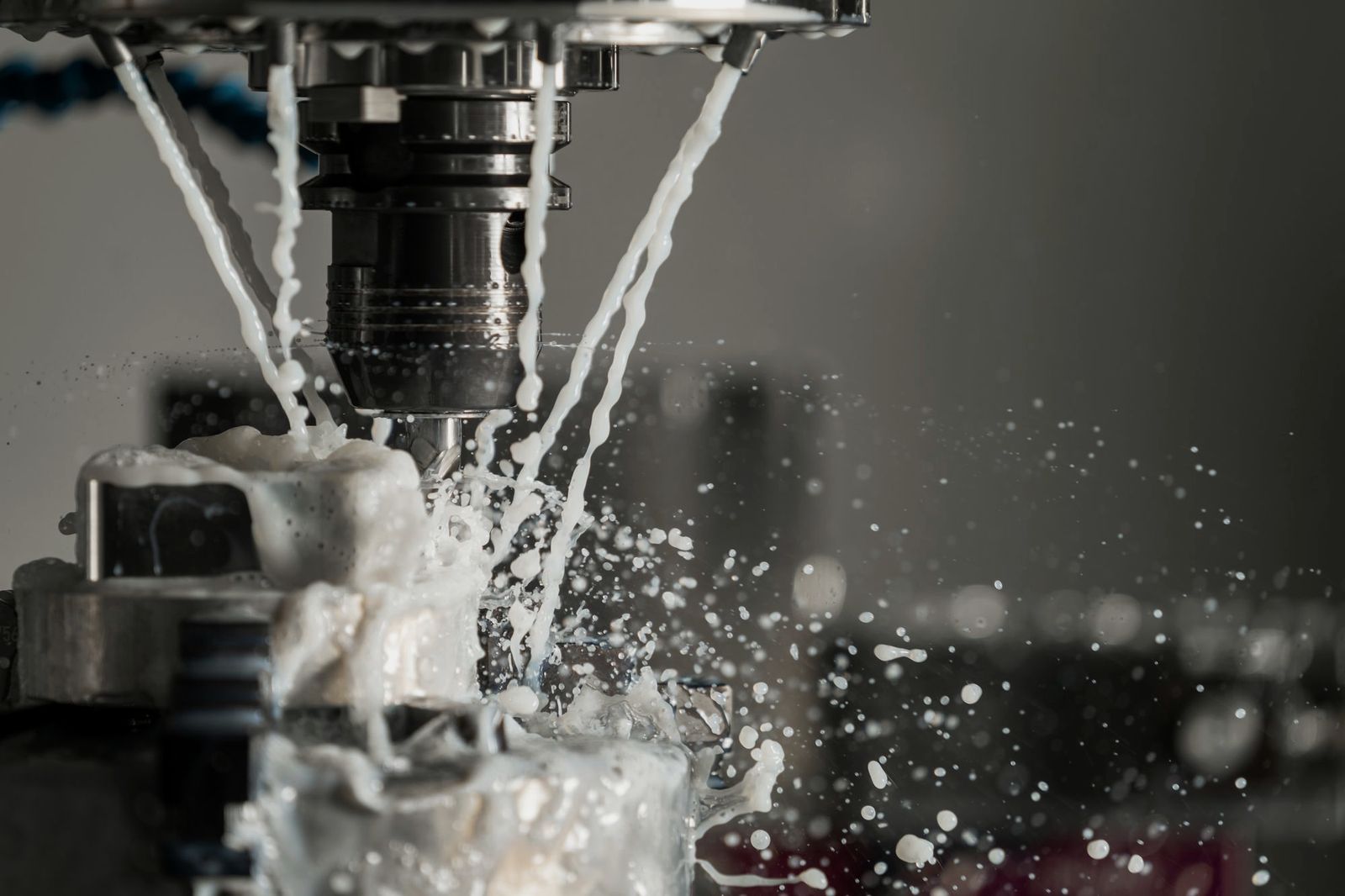Illustrative photo: a milling cutter working a metal part under coolant spray
