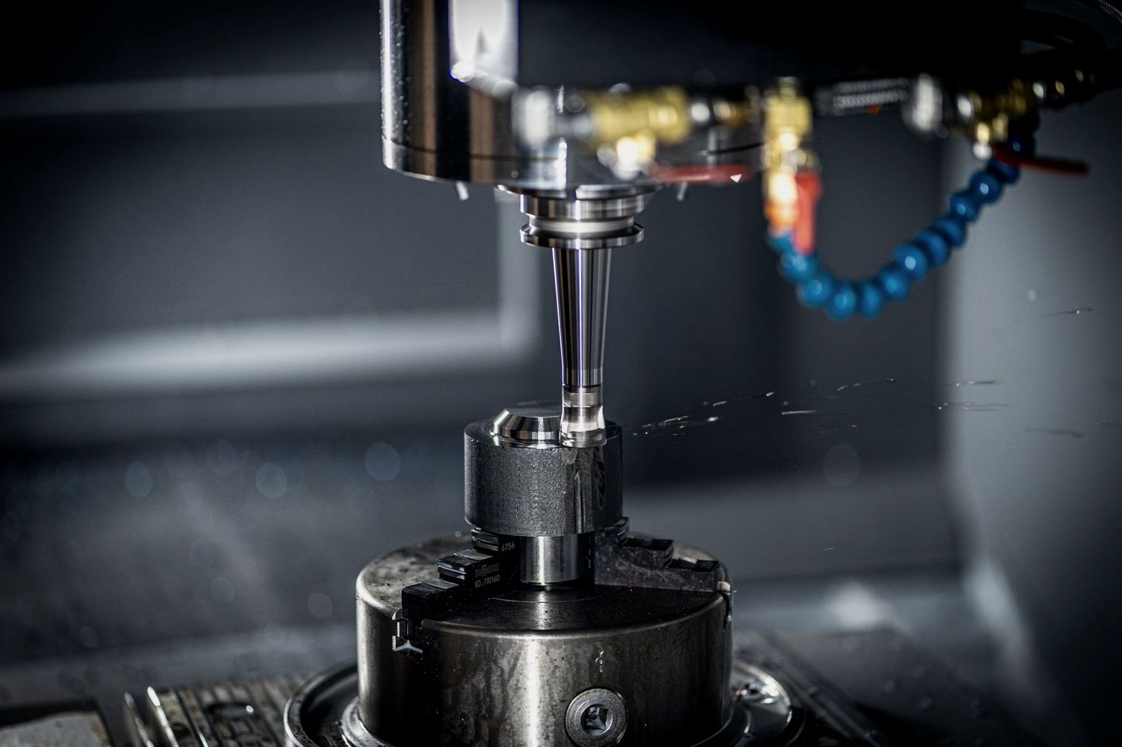 Illustrative photo: a machine spindle and cutting tool above a part held in a chuck