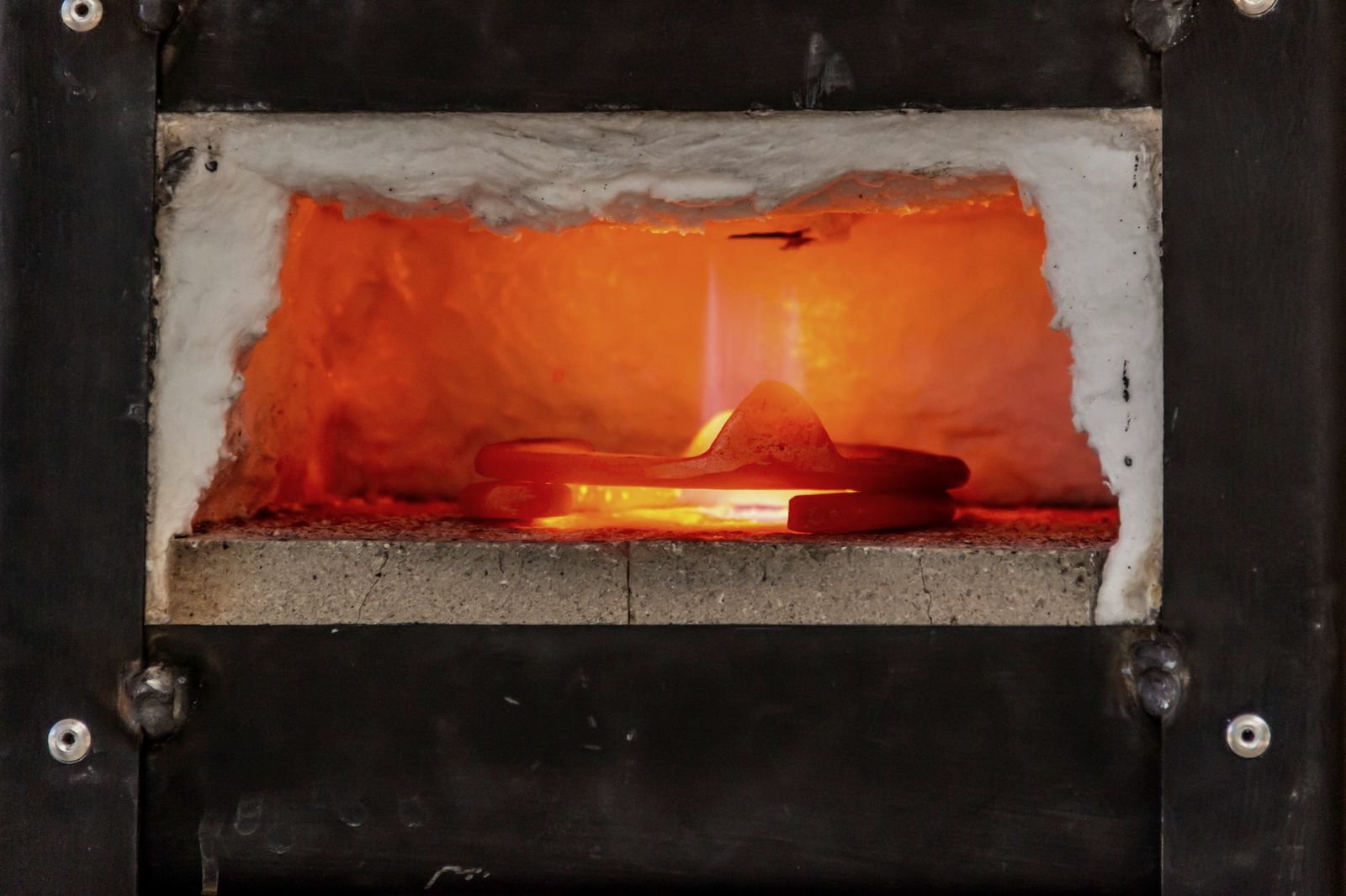 Illustrative photo: steel heated to a red glow inside a furnace